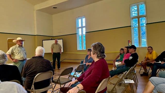 Community members seated in a meeting hall listening to a presentation during the Alpine open house discussion.